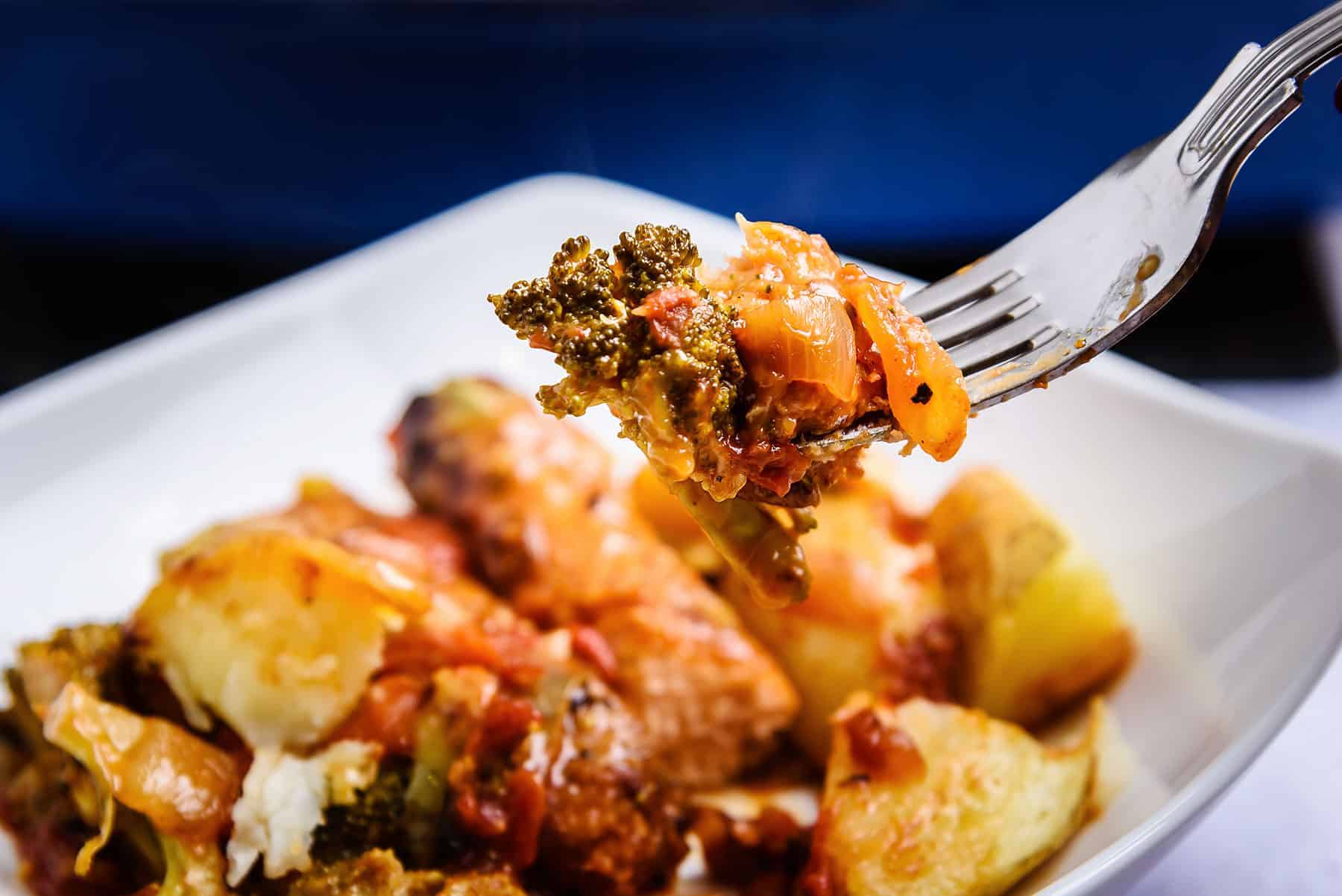 Broccoli with sausage and onion on a fork