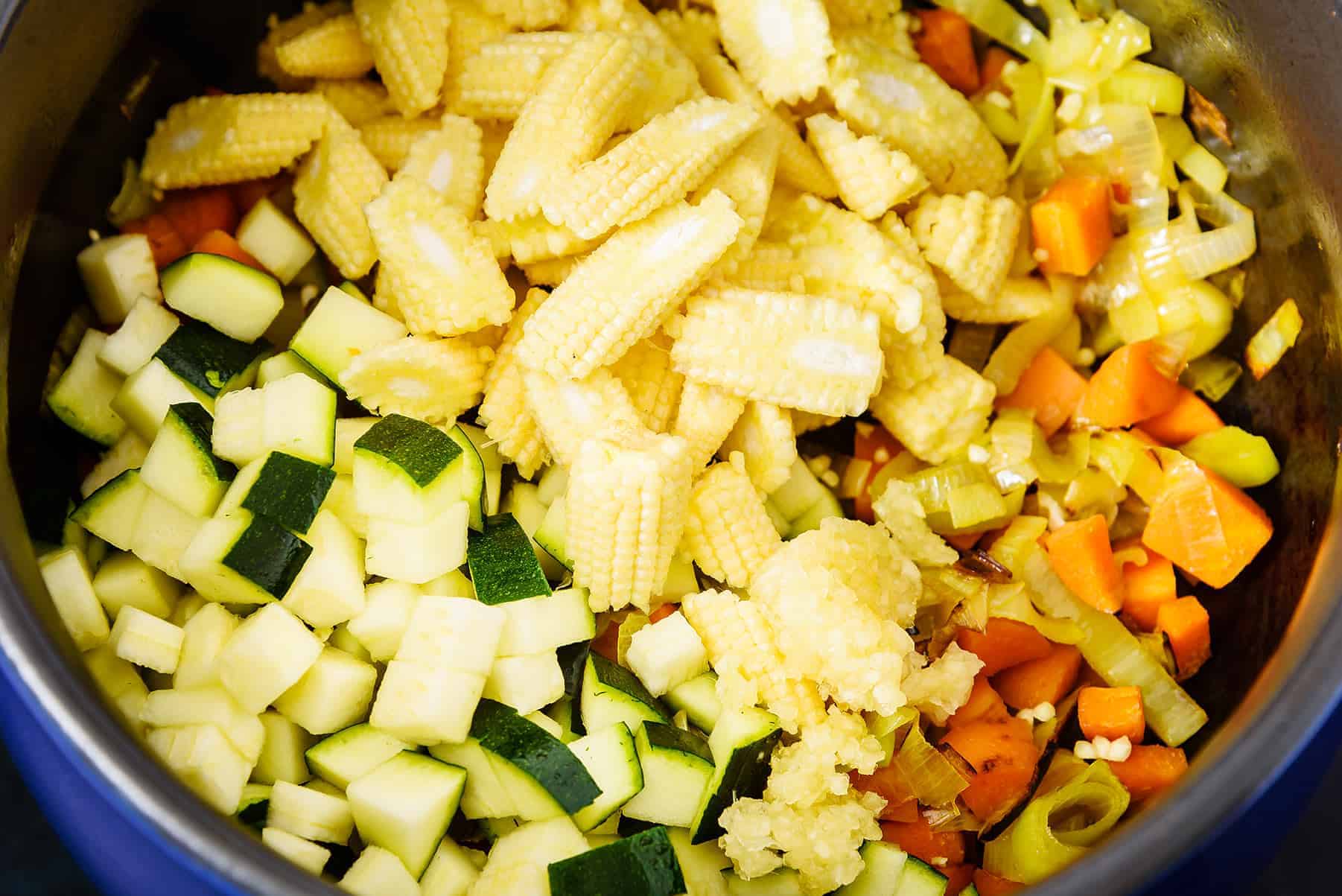 Adding courgettes and baby corn to the pan