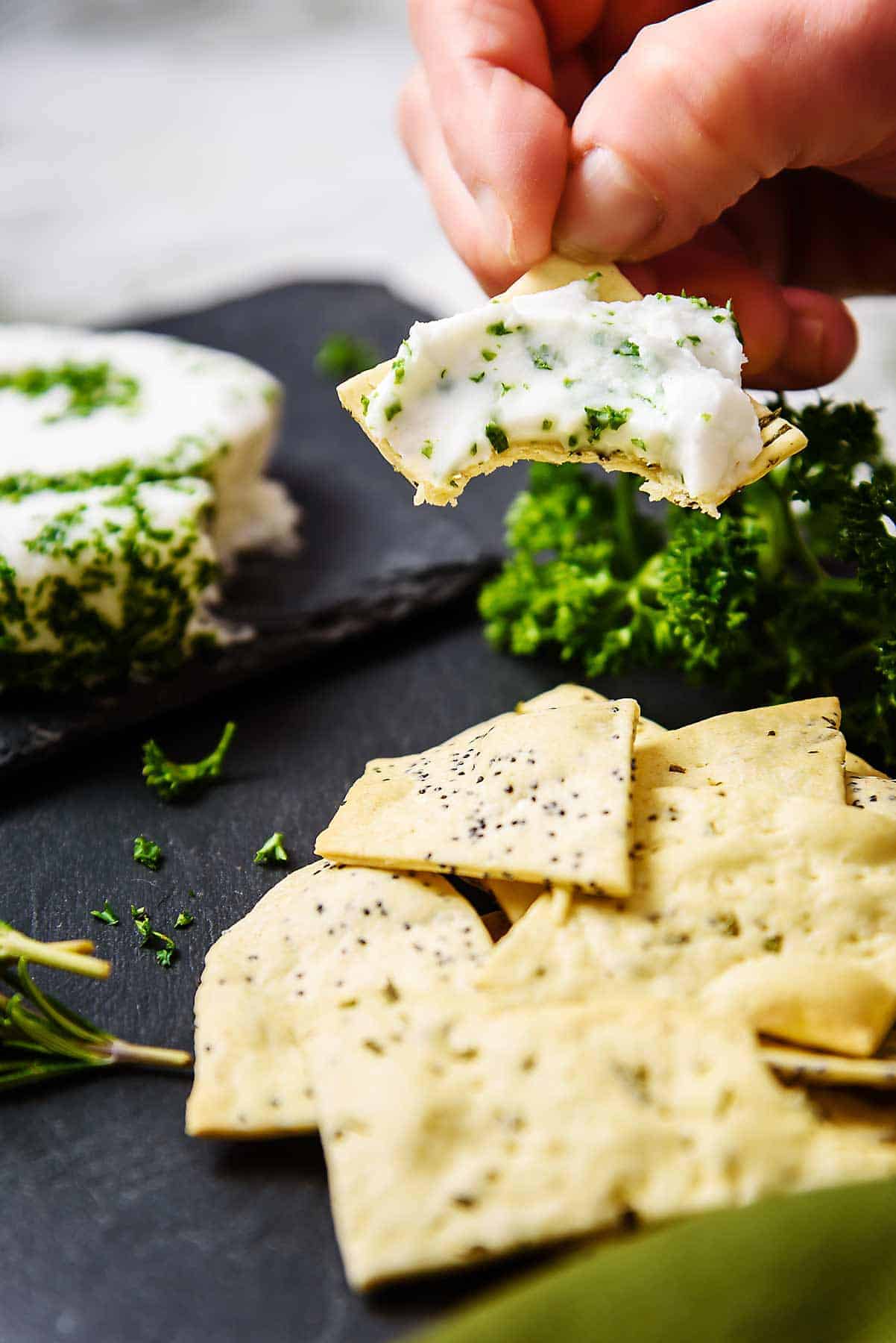 A bite taken from cheese-covered Vegan Rosemary & Poppyseed Crackers