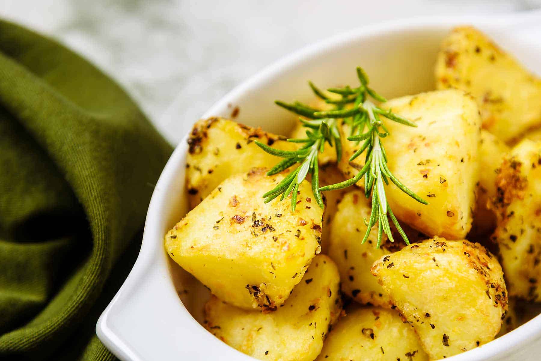 Close up of Vegan Rosemary & Garlic Roast potatoes with sprigs of rosemary