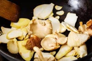 Sautéing mushrooms and garlic in a wok