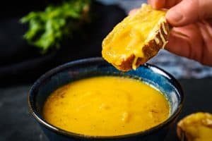 Vegan Onion & Tarragon Soup with a piece of melted cheese on toast