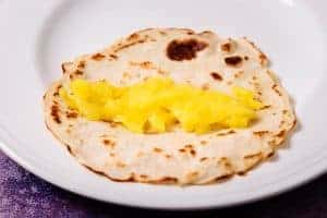 Filling a cooked crepe with mashed mango