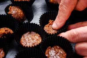 Finger pushing biscuit and butter mixture into mini muffin cases