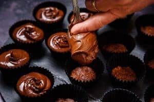 Placing the biscoff and chocolate mixture in the mini muffing cases