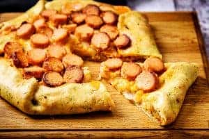 Cooked Spicy Onion & Sausage Galette on a serving board with slice cut