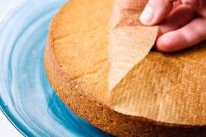 Peeling back the baking paper from the cooked cake