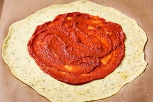 Rolled pastry dough with tomato puree spread on
