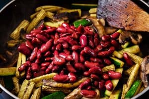 Cooked vegetables in a pan with beans added