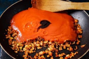 Pan with cooked onions with passata and balsamic drizzle added