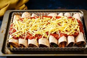 Tortillas rolled and topped with cheese ready for the oven