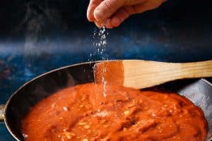 Sprinkling seasoning on the sauce in the pan
